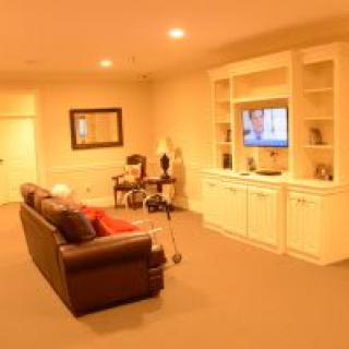 A cozy living room with a sofa facing a television built into a wall unit.