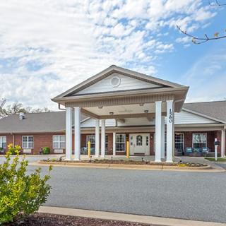 A building with a prominent entrance featuring columns under a partly cloudy sky.