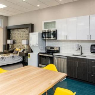 A modern open-concept kitchen and living area with a dining table and yellow chairs.