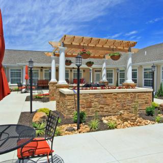 A beautifully landscaped courtyard featuring a pergola, outdoor seating, and vibrant garden elements.