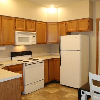 A modern kitchen with wooden cabinets and essential appliances.