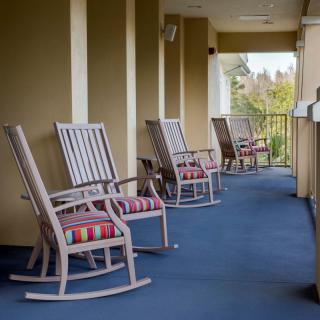 A row of rocking chairs lined up on a balcony.