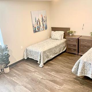 A minimalist bedroom with two twin beds, wooden flooring, and simple decor.