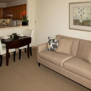 A cozy living room with a beige sofa and an adjacent dining area in a modern apartment.