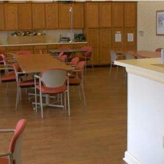 A spacious dining area with wooden floors, featuring tables and chairs arranged for seating.