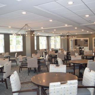 A spacious dining room with multiple tables and chairs, featuring modern lighting.