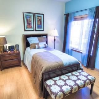 A neatly decorated bedroom featuring a single bed, nightstand, and framed artwork.