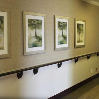 A hallway decorated with framed paintings and equipped with a handrail.