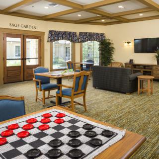 A cozy game room with a checkers board, comfortable seating, and a television for entertainment.