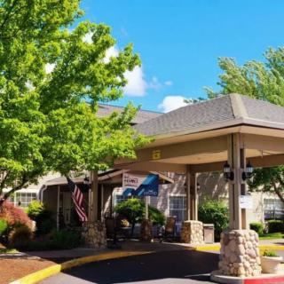 A sunny view of a building entrance surrounded by trees and flags.
