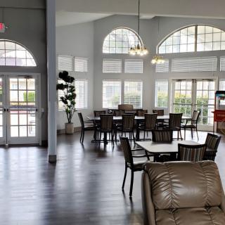 A spacious and well-lit lobby area with tables, chairs, and large windows.
