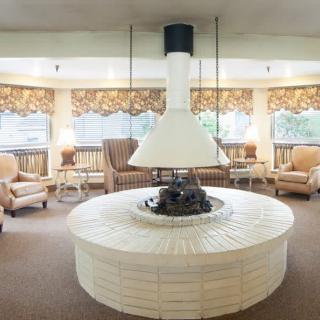 A cozy lounge area with a central fireplace and comfortable seating.