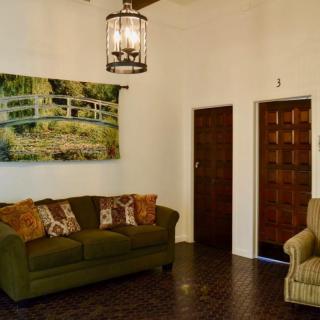 A cozy living room featuring a green sofa, armchair, and a landscape painting on the wall.