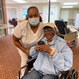 A smiling nurse poses with an elderly resident in a care facility, showcasing the compassionate environment of elder care.