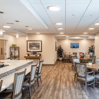 A spacious dining area with wooden flooring, decorated with tables and chairs.