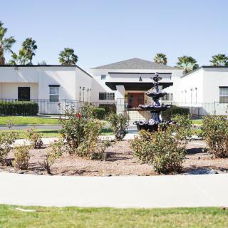 A modern building with a landscaped garden and a fountain in front.