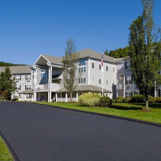 A large residential building surrounded by trees and greenery under a clear blue sky.