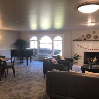 A cozy living room featuring a grand piano, comfortable seating, and a decorated fireplace.