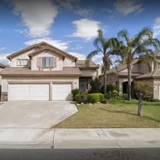 A suburban house with a driveway and palm trees.