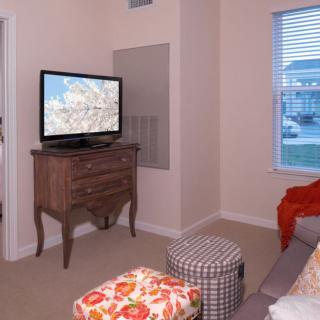 Cozy living room with a television on a vintage dresser and colorful ottomans.