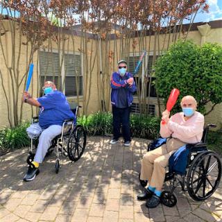 Elderly residents enjoying an engaging outdoor activity with colorful bats.