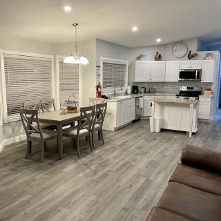 A modern open-concept kitchen and dining area featuring white cabinets, wood flooring, and ample lighting.