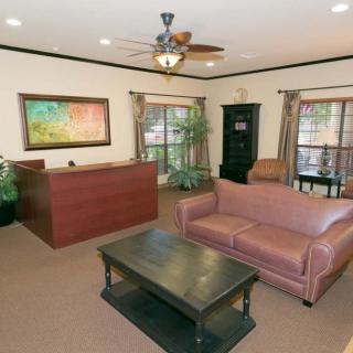 A cozy living room or lobby area featuring a sofa, coffee table, desk, and artwork on the wall.