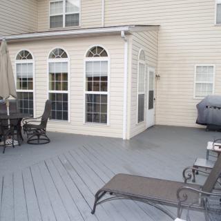 A spacious outdoor deck with patio furniture and a grill alongside the house.