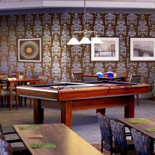 A stylish restaurant interior featuring a pool table and seating area, with decorative wall art and ambient lighting.