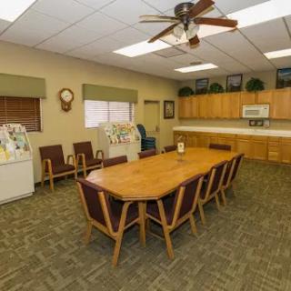 A spacious meeting room equipped with a large wooden table and kitchenette, ideal for team gatherings.