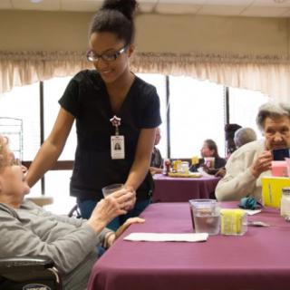 A healthcare professional assists an elderly person in a nursing home setting.