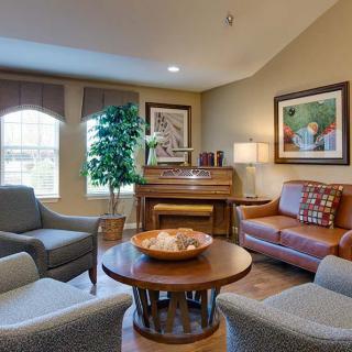 A cozy living room with a sofa, armchairs, and a piano.