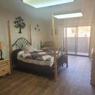 A cozy bedroom with a wooden floor, featuring a four-poster bed, skylight, and sliding glass doors.