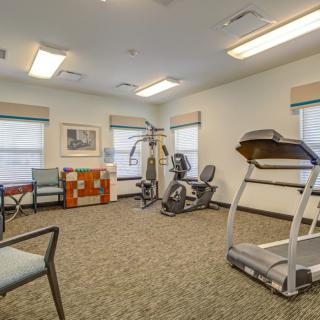 A small fitness room with exercise equipment and seating.