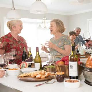 A group of friends enjoying food and drinks together in a kitchen setting.