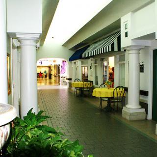 A serene corridor within a shopping mall, featuring elegant columns and small seating areas.