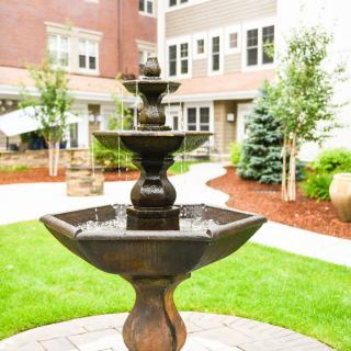 A decorative fountain in a landscaped courtyard surrounded by apartment buildings.
