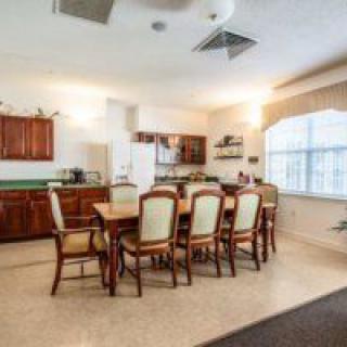 A spacious kitchen and dining area featuring a wooden table with chairs and large windows.