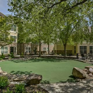 A landscaped outdoor area with trees and a building in the background.