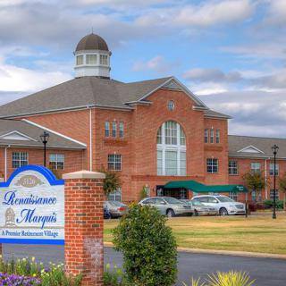 A grand brick hotel with a large entrance and a nearby parking lot under a cloudy sky.