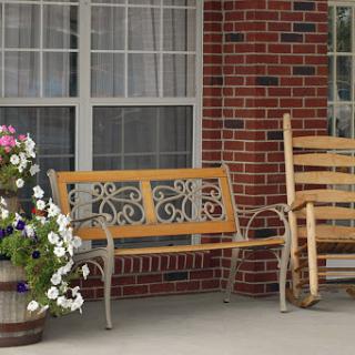 A cozy outdoor setting featuring wooden benches, a flower pot filled with vibrant flowers, and a brick wall backdrop.