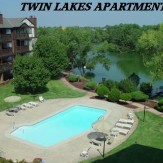 A serene view of Twin Lakes Apartments featuring a sparkling pool and lush surroundings.