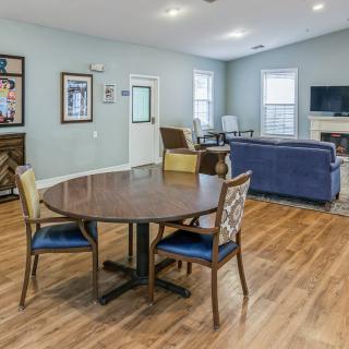 A cozy living room with a round table, chairs, and a blue couch on hardwood flooring.