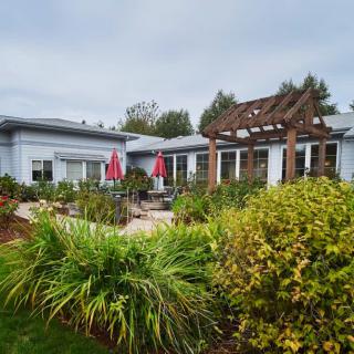 A cozy backyard with a well-maintained garden, featuring a patio and pergola adorned with red umbrellas.