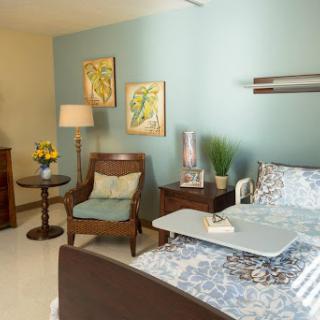 A cozy and well-decorated hospital room featuring calming blue walls and inviting furniture.