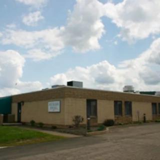 A small industrial building under a cloudy sky.