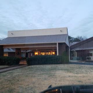 An evening view of a modern building with warm lights illuminating its entrance.