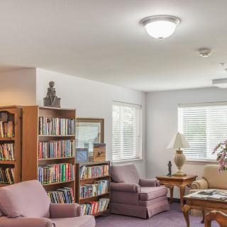 A cozy living room with bookshelves and armchairs, perfect for reading.