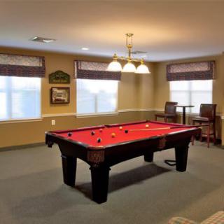 A cozy game room featuring a pool table with red felt under a hanging chandelier.