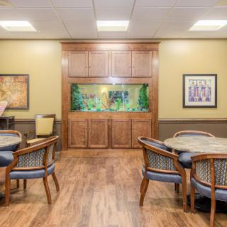 A modern dining area with wooden flooring, featuring an aquarium and artwork on the walls.